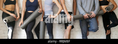 Groupe photo horizontale young people wearing activewear holding yoga mats debout près de mur avant ou après la formation, de la santé et actifs FRV Banque D'Images