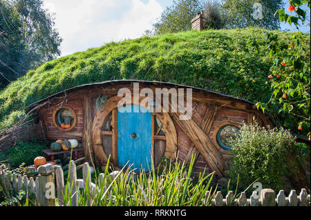 Hobbiton movie set, Matamata, Nouvelle-Zélande. . Charmant petit Hobbit chambre avec porte turquoise, vert, dans un paysage de colline ensoleillée et ciel bleu Banque D'Images