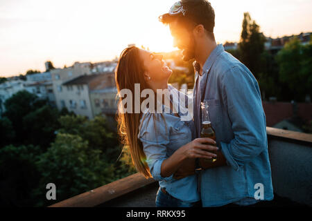 Couple flirting tout en prenant un verre sur la terrasse sur le toit Banque D'Images