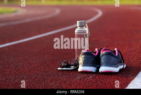 Bouteille d'eau et chaussures sur la piste d'athlétisme à l'après-midi Banque D'Images