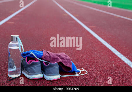 Sac à dos et une bouteille d'eau sur la piste d'athlétisme à l'après-midi Banque D'Images