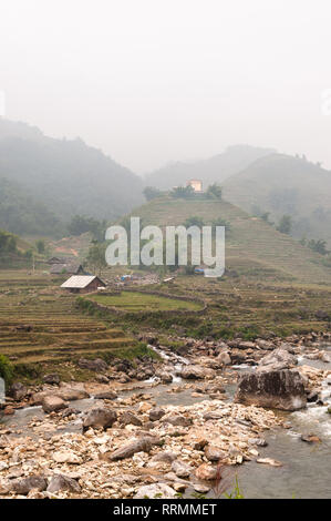 Collines en terrasses et les maisons de ferme dans le brouillard avec river en premier plan, Sa Pa, Vietnam Banque D'Images