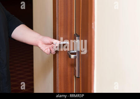 Mettre la main féminine dans l'interrupteur de la carte-clé pour ouvrir la porte de la salle de l'hôtel. Carte magnétique holding pour le contrôle d'accès porte carte clé de numérisation pour verrouiller et déverrouiller Banque D'Images