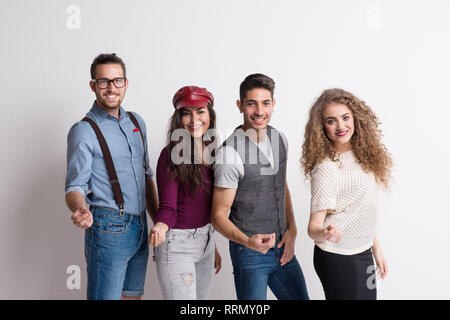 Portrait d'un jeune groupe d'amis l'article et d'avoir du plaisir dans un studio, portant des vêtements intelligents occasionnels. Banque D'Images