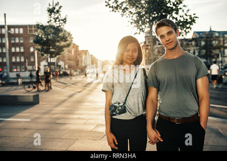 Smiling couple holding hands debout ensemble dans la ville Banque D'Images