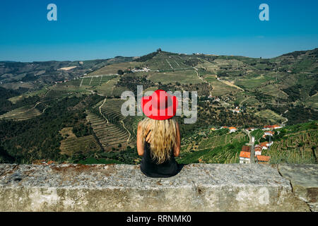 Woman in red hat appréciant ensoleillée, vaste paysage vallonné, vue sur le Portugal Banque D'Images