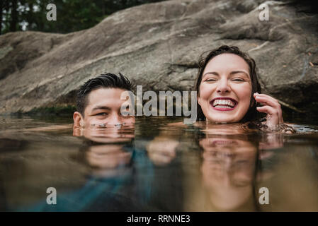 Portrait jeune couple ludique nager dans le lac Banque D'Images