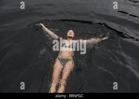 Serene young woman in bikini flottant dans le lac Banque D'Images