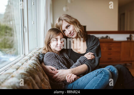 Affectueux Portrait mère et fille de câlins sur canapé Banque D'Images