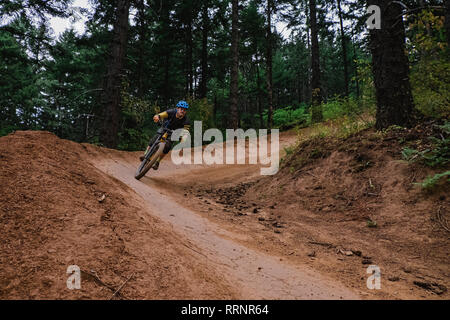 Man mountain biking on dirt trail in woods Banque D'Images