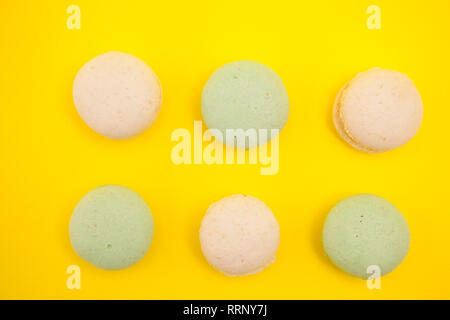 Vue de dessus de Peach et vert macarons en rangées sur le fond jaune. Assortiment de macarons Banque D'Images