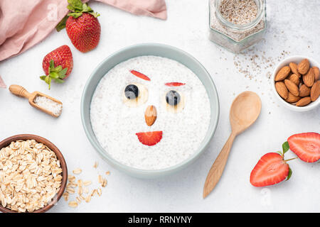 Chia pudding aux fruits et noix pour les enfants. Drôle de visage à base de fruits et de noix sur le yaourt avec les graines de chia. Repas Petit déjeuner pour les enfants Banque D'Images