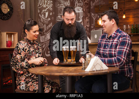 Hipster barman responsable de l'ordre de belle jeune couple.Grande Pub. Banque D'Images