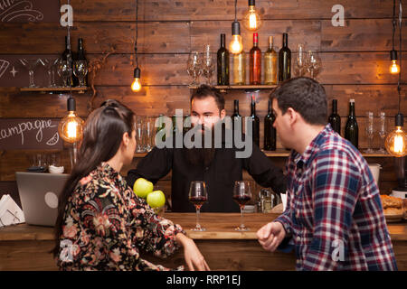 Couple talking to barman derrière comptoir dans un café. Hipster barman. Banque D'Images