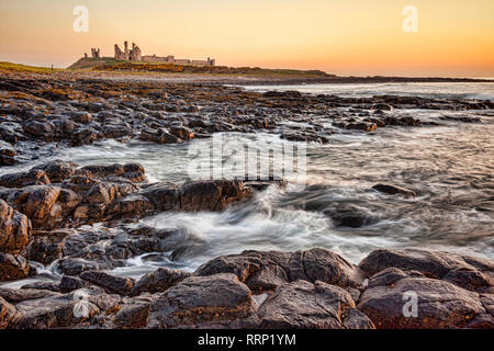 Lever du soleil au château de Dunstanburgh sur la côte de Northumberland, Angleterre du Nord-Est. Banque D'Images