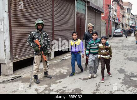 Enfants cachemiriens passons un trooper paramilitaires d'alerte permanent à l'extérieur de la chambre de la top chef séparatiste Yasin Malik, lors d'une descente par les agents du renseignement indien à Srinagar, au Cachemire. L'Enquête nationale Agency (NIA) Mardi effectuée des recherches sur top chefs séparatistes dans la vallée du Cachemire dans un cas, le financement de la terreur ont déclaré. La NIA ont été accompagnés par la police locale et des CRPF. Pendant ce temps, des affrontements ont éclaté dans Maisuma localité peu après l'agence de détectives Enquêtes nationales mené des raids sur les haut dirigeants séparatistes. Banque D'Images