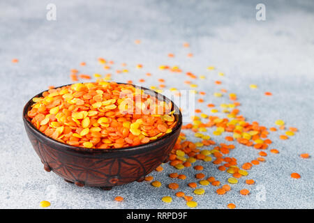 Assortiment de lentilles multicolores à sec dans un bol d'argile close-up. Jaune et rouge, les céréales. Variété des libéraux. De délicieux aliments sains. Focus sélectif et Banque D'Images