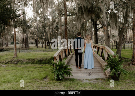 Belle robe de demoiselle d'honneur la Femme en bleu et le Bouquet avec sa date au cours d'une célébration de mariage à l'extérieur de l'événement dans les bois en tenant l'orifice Couple Banque D'Images