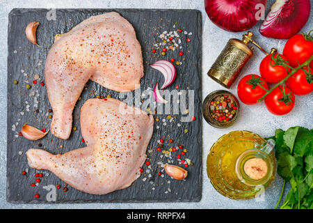 Cuisses de poulet non cuit brut, pilons sur ardoise, la viande avec les ingrédients pour la cuisson - oignons rouges, tomates, ail, poivrons, persil (la coriandre Banque D'Images
