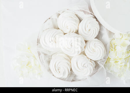 Guimauve tendre blanc dans un cadre blanc sur fond clair fleurs de décoration. La structure horizontale. Vue de dessus. Banque D'Images