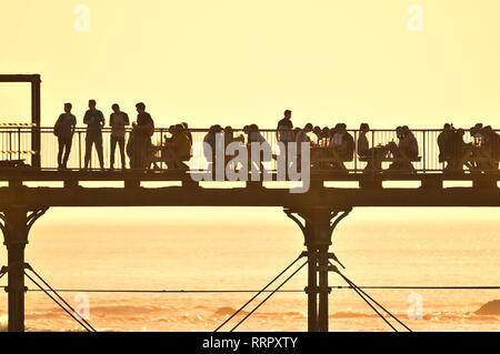 Pays de Galles Aberystwyth UK, mardi 26 février 2019. Météo France : les gens sur la jetée et la promenade à Aberystwyth tirer le maximum de la sensationelle chaude et ensoleillée 'winter' météo . La température d'hiver record britannique a de nouveau été rompu aujourd'hui, à Porthmadog, également sur la côte de la Baie de Cardigan, l'enregistrement d'une incroyable 20.8ºC cet après-midi. Crédit photo : Keith morris/Alamy Live News Banque D'Images