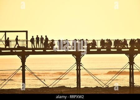 Pays de Galles Aberystwyth UK, mardi 26 février 2019. Météo France : les gens sur la jetée et la promenade à Aberystwyth tirer le maximum de la sensationelle chaude et ensoleillée 'winter' météo . La température d'hiver record britannique a de nouveau été rompu aujourd'hui, à Porthmadog, également sur la côte de la Baie de Cardigan, l'enregistrement d'une incroyable 20.8ºC cet après-midi. Crédit photo : Keith morris/Alamy Live News Banque D'Images