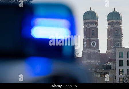 26 février 2019, Bavaria, Munich : une lumière bleue d'une patrouille de police peut être vu en face des tours de l'église Frauenkirche. Photo : Lino Mirgeler/dpa Banque D'Images