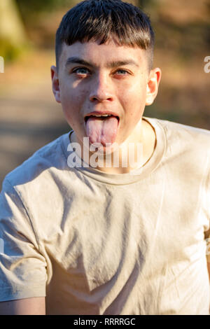 Portrait of a Young boy par une chaude journée de printemps avec sa langue qui sort Banque D'Images