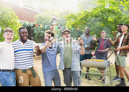 Heureux et enthousiaste d'amis masculins de boire une bière et de chanter pendant un barbecue Banque D'Images