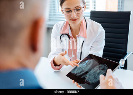 Médecin concerné montrant x-ray pour homme patient Banque D'Images