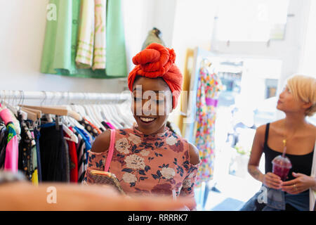 Young woman using smart phone in clothing store Banque D'Images