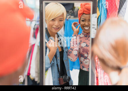 Les jeunes femmes friends shopping à mirror in clothing store Banque D'Images