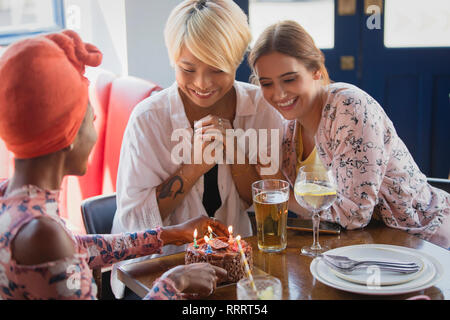 Les jeunes femmes friends celebrating birthday avec gâteau au restaurant Banque D'Images