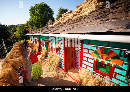 Femme indienne devant sa maison Kumaoni tipycal, où un tas de blé est le séchage au soleil, Kala Agar Kumaon Hills village,, Uttarakhand, Inde Banque D'Images