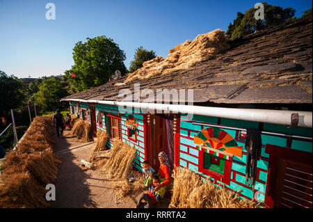 Femme indienne devant sa maison Kumaoni tipycal, où un tas de blé est le séchage au soleil, Kala Agar Kumaon Hills village,, Uttarakhand, Inde Banque D'Images