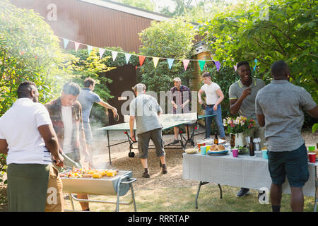 Amis de jouer au ping-pong, bénéficiant d'un barbecue Banque D'Images