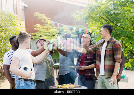 Heureux homme friends toasting drinks sur barbecue in backyard Banque D'Images