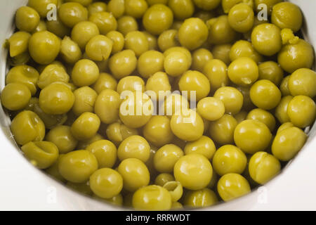 Close-up of green pois chiches dans une boîte de conserve ouverte sur fond blanc Banque D'Images