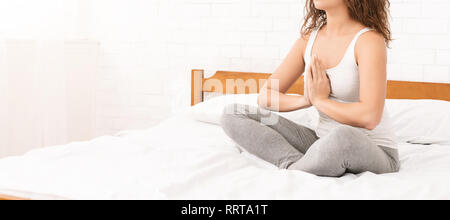 Young caucasian woman practicing yoga in bed Banque D'Images