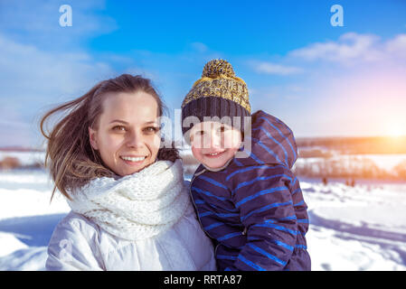 Maman avec son fils dans ses bras à l'hiver en ville. Les soins et l'appui d'un petit enfant à l'air libre. Happy smiling people having a reste dans le Banque D'Images