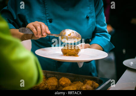 Close up image d'un chef cuisinier qui sert un meatball dans un lieu pendant la préparation dans la cuisine. Banque D'Images