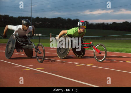 Les athlètes paraplégiques en accélérant le long de la piste en course en fauteuil roulant de sport Banque D'Images
