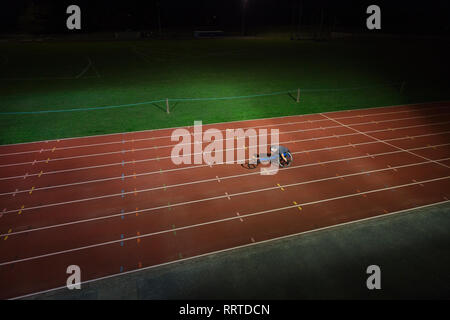 Athlète paraplégique en accélérant le long de la voie des sports en fauteuil roulant de nuit course Banque D'Images