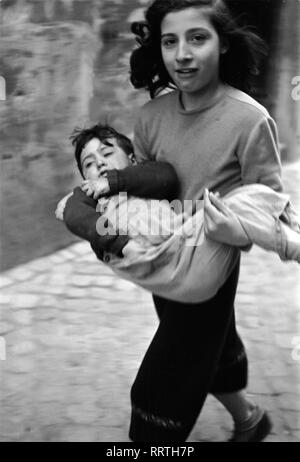 Voyage Italie - l'Italie en 1950 - Enfants - soeurs et frères à Rome - Trastevere, trimestre. Ein Mädchen trägt ein Kleinkind durch die Straßen von Trastevere en Rom. Photo Erich Andres Banque D'Images