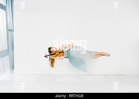 Girl in blue dress holding violin dans l'air with copy space Banque D'Images