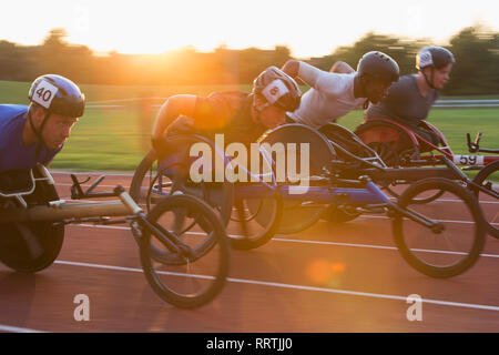 Les athlètes paraplégiques en accélérant le long de la piste en course en fauteuil roulant de sport Banque D'Images