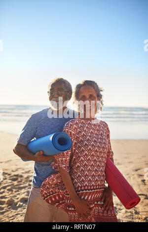 Portrait of happy senior couple avec un tapis de yoga sur sunny beach Banque D'Images