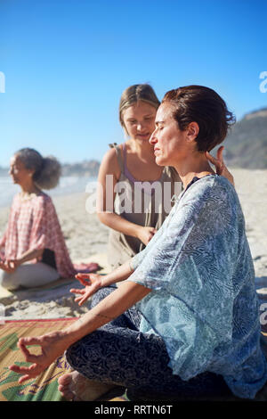 Serene woman meditating on sunny beach au cours de yoga retreat Banque D'Images