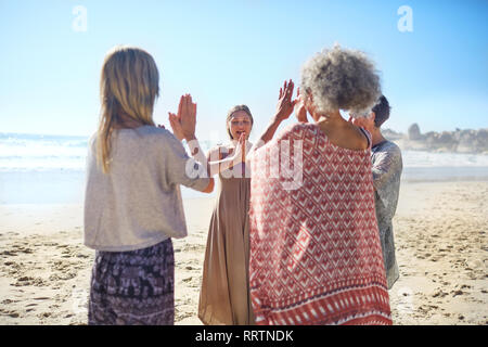 Les femmes amis avec les mains jointes en cercle sur la plage ensoleillée au cours de yoga retreat Banque D'Images