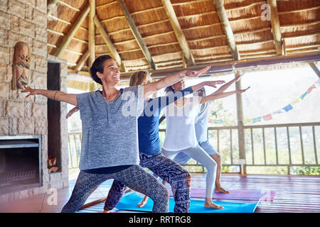 Happy woman practicing yoga guerrier 2 poser dans hut au cours de yoga retreat Banque D'Images